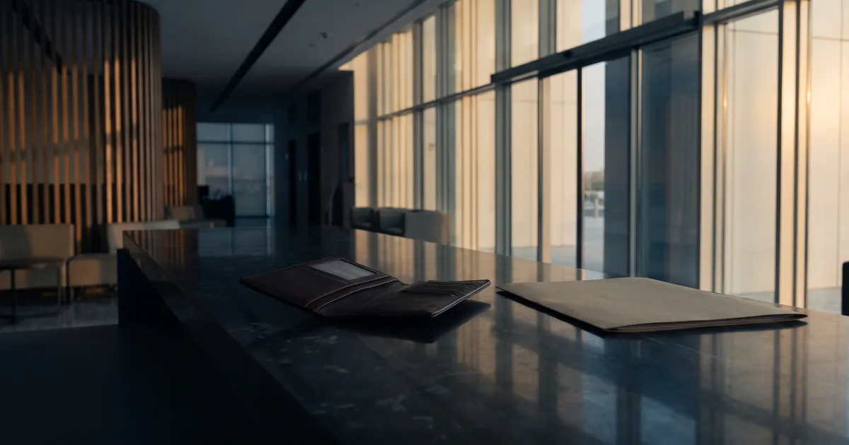 An empty leather travel wallet lying open on a stone counter in a softly lit UAE government service centre at dusk