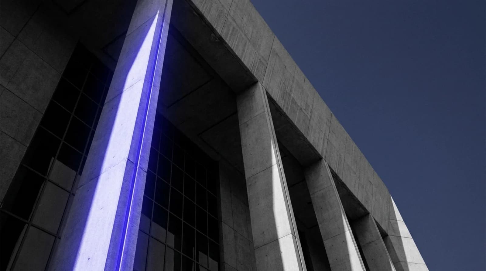 Pillars of an Abu Dhabi judicial building from a low angle in monochrome navy — criminal lawyers in Abu Dhabi